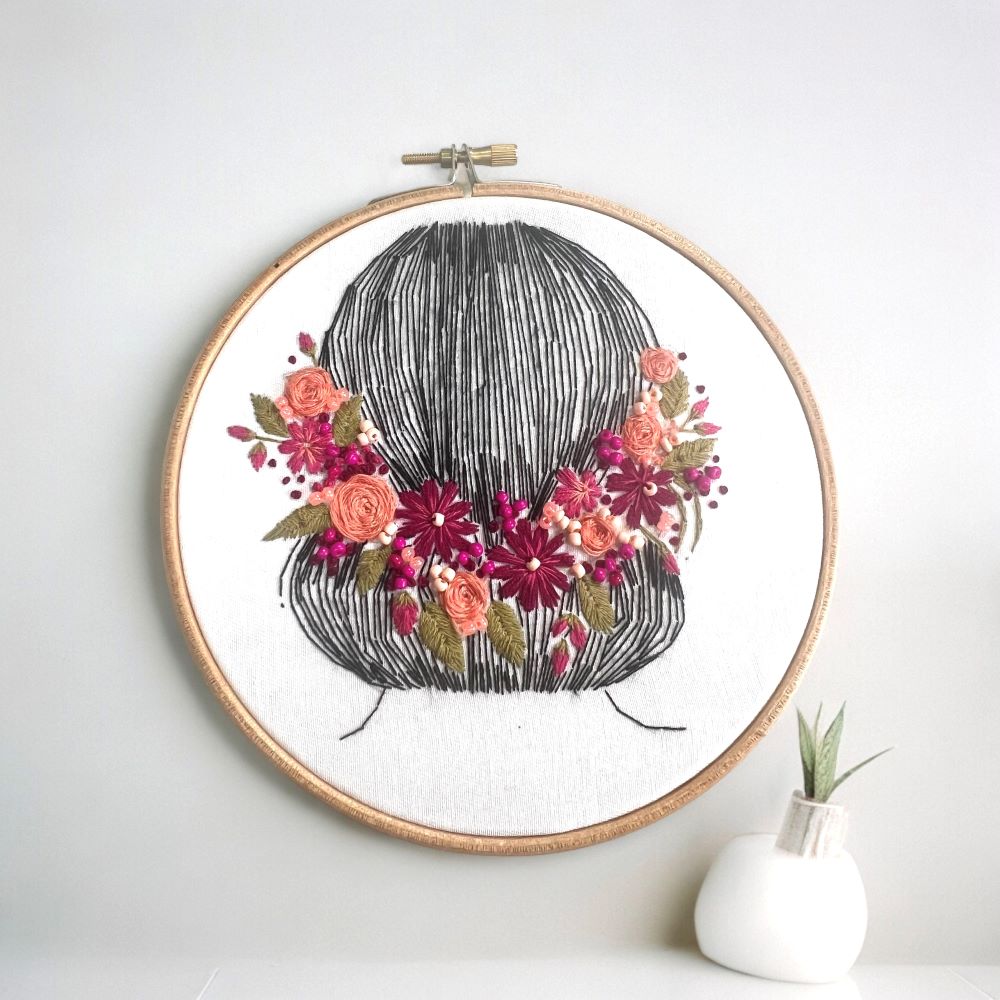 embroidery pattern completed against white wall beginner friendly embroidery kit including rose stitch, satin stitch, french knot and back stitch